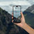 Hand, die ein  View 2  Smartphonemit Bergen im Hintergrund manipuliert